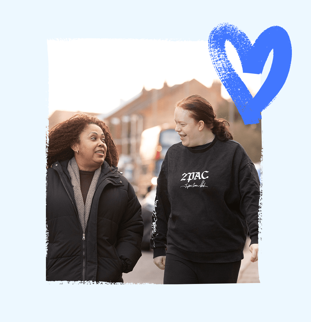 Service user and a support worker walking together down a bustling street towards shops