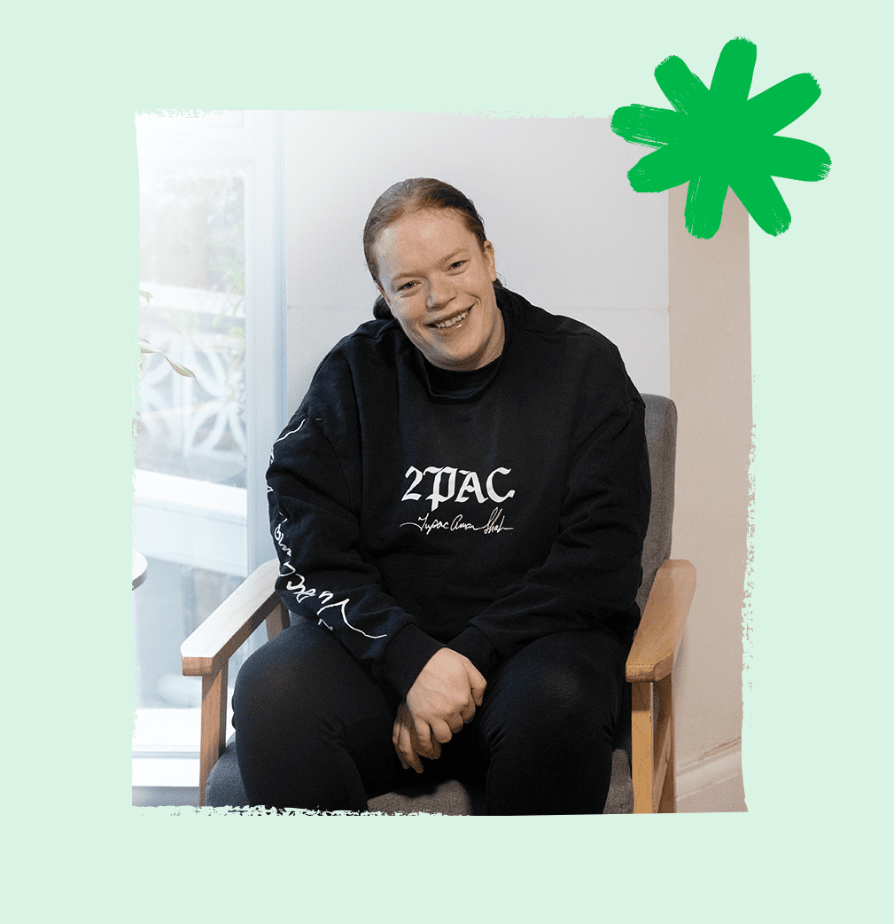 A service user smiling and looking relaxed while sitting comfortably in her own home