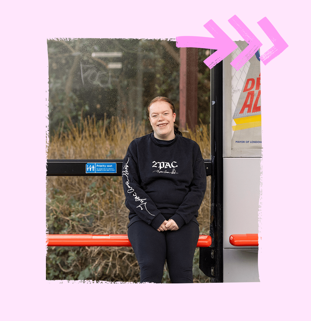 A service user is standing alone at a bus stop, patiently waiting for the bus to arrive.