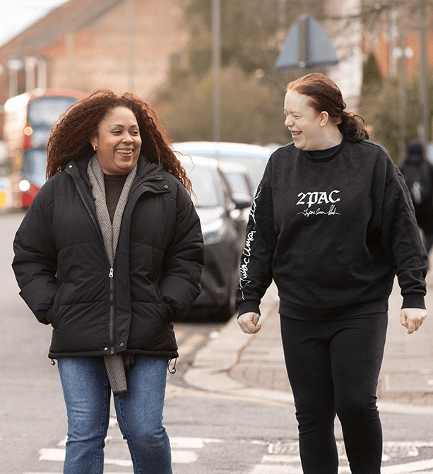 Service user and a support worker walking together down a bustling street towards shops